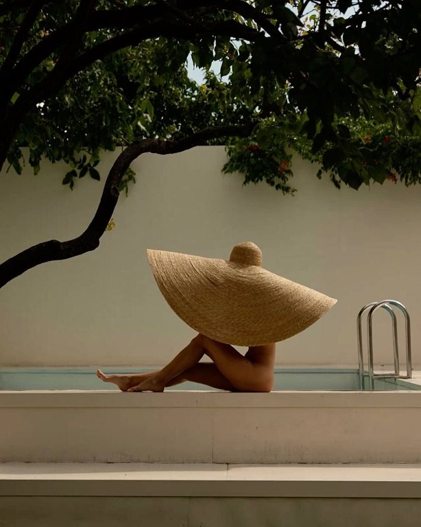Wide straw hat poolside under the trees