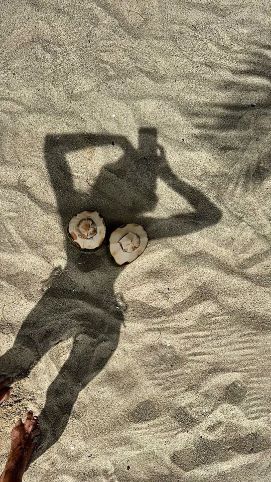 Shadow of a sunbather cast on warm sand